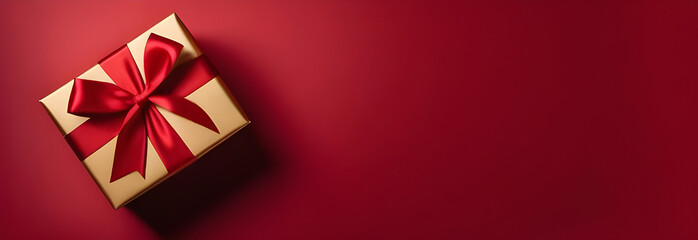 Gift in gold packaging with a red ribbon on a red background, top view. Banner for Valentine's Day, March 8, birthday.