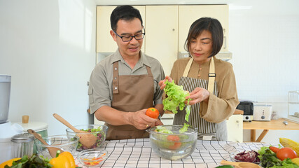 Beautiful Asian senior couple preparing fresh organic vegetables for salad. Healthy eating concept.