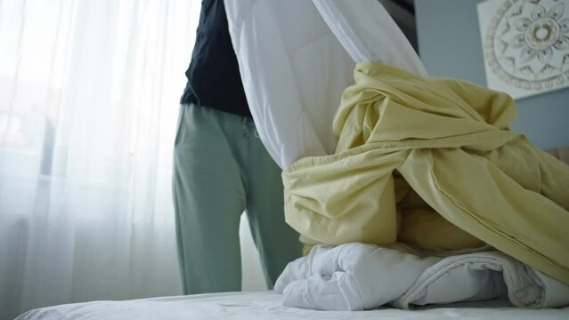 Woman replacing bed linen in room. Female making bed in bedroom. Routine chores and housework