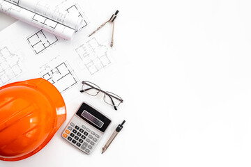 Flat lay of drawing blueprints for architectural project. Helmet on architect office desk
