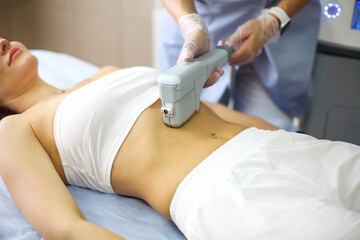Cropped shot of young fit blonde woman client receiving laser hair removal procedure on body in...
