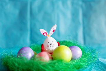 Colorful Easter eggs, green nest and bunny rabbit