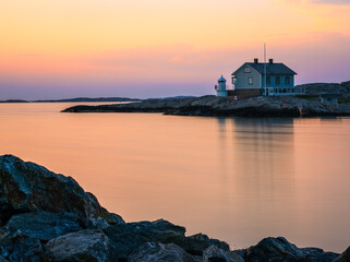 House and lighthouse on peninsula of a swedish coast in evening sunset light - long exposure