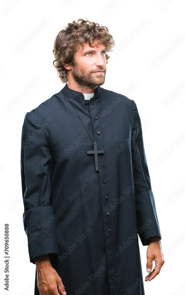 Sticker Handsome hispanic catholic priest man over isolated background looking away to side with smile on face, natural expression. Laughing confident.