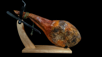 Serrano ham leg in its ham holder. Black background. Copy space. (1)