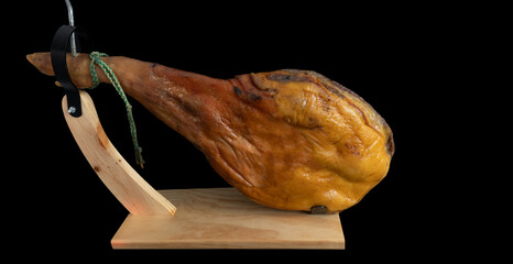 Serrano ham leg in its ham holder. Black background. Copy space. 4