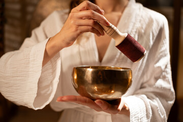 Woman in white robe holding Tibetan Singing Bowl for meditation.