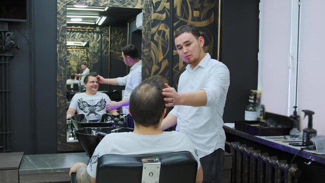 A hairdresser discusses the details of a haircut with a male client before starting work at the barbershop