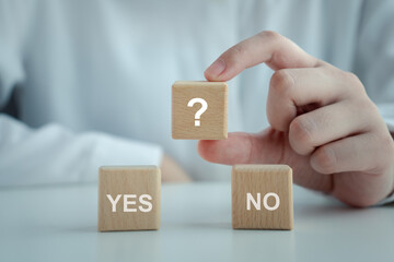 Woman hand holding question mark on wooden circle with YES and NO word. Think with Yes Or No...