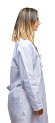 Fototapeta premium Young beautiful doctor woman headphones over isolated background looking to side, relax profile pose with natural face with confident smile.