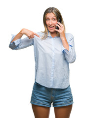 Fototapeta premium Young beautiful woman talking on smartphone over isolated background with surprise face pointing finger to himself