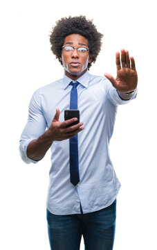Afro american business man texting using smartphone over isolated background with open hand doing stop sign with serious and confident expression, defense gesture