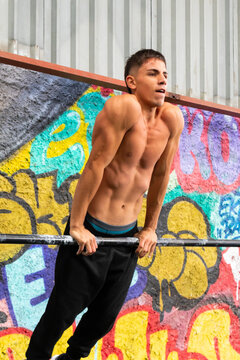 Shirtless sportsman doing pull ups on bar