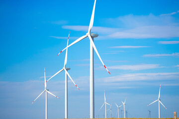 Fleet of power generators in motion. The blades of the wind farm rotate against the sky. The...