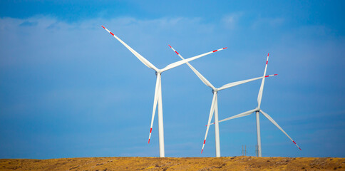 Fleet of power generators in motion. The blades of the wind farm rotate against the sky. The concept of extracting electricity from renewable sources. Wind turbine to generate electricity.