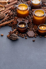 Soy scented candle in a jar. Coffee beans, anise, cinnamon spices. The candles are burning. Dark copy space background