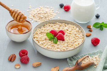 Bowl of porridge or oatmeal with fruits, nuts and honey. Breakfast cooking.