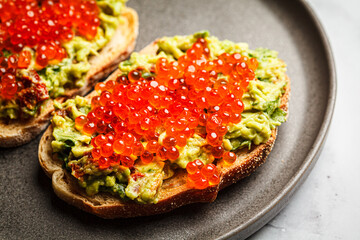 Red caviar and guacamole toast with rye bread.