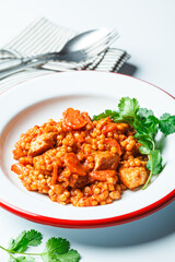 Ptitim with chicken, vegetables and cilantro, white background. Traditional Israeli food.