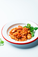 Ptitim with chicken, vegetables and cilantro, white background. Traditional Israeli food.
