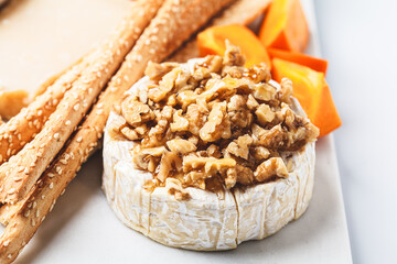 Camembert cheese with walnuts and honey on cheese board for party.