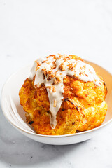 Whole roasted spicy cauliflower with tahini dressing and caramelized onions.