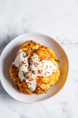 Whole roasted spicy cauliflower with tahini dressing and caramelized onions.