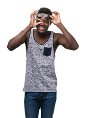 Young african american man with happy face smiling doing ok sign with hand on eye looking through fingers