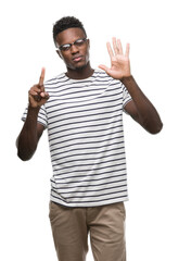 Young african american man wearing glasses and navy t-shirt showing and pointing up with fingers number six while smiling confident and happy.
