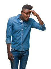 Fototapeta premium Young african american man over isolated background very happy and smiling looking far away with hand over head. Searching concept.