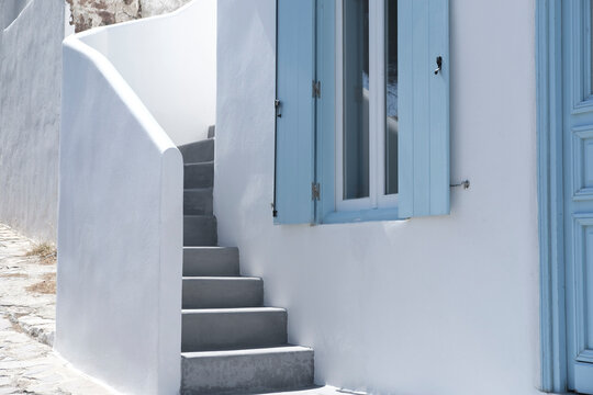 Fototapeta greek traditional island house with blue wooden windows and doors, whitewashed cement concrete streets and stairs