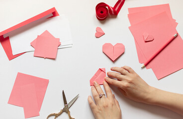 Woman's hands making pink origami paper heart for Valentine's day