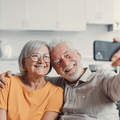 Happy old couple taking selfie on cellphone, smiling senior mature spouses middle aged wife and retired husband laughing holding phone make self portrait on smartphone camera, focus on mobile display. - obrazy, fototapety, plakaty