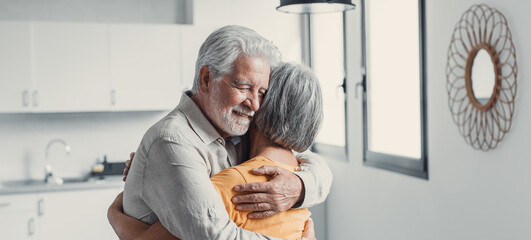 Happy mature couple in love embracing, laughing grey haired husband and wife with closed eyes, horizontal banner, middle aged smiling family enjoying tender moment, happy marriage, sincere feelings.