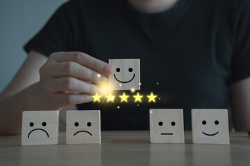 Woman hand choosing happy smiling face and 5 star on wooden block. Feedback rating and Customer experience, World mental health day, Think positive, Emotion, Satisfaction score concept.
