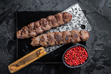 Urfa kebab, ground beef and lamb meat grilled on skewers. Black background. Top view