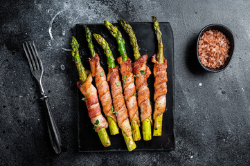 Asparagus Baked with bacon and spices. Black background. Top view