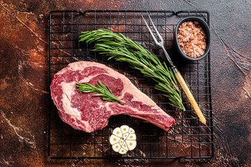 Raw uncooked dry aged beef  tomahawk or rib eye steak. Dark background. Top view - obrazy, fototapety, plakaty