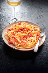 Carbonara pasta dish, traditional Italian spaghetti with pancetta and cheese, with a fork and a glass of wine