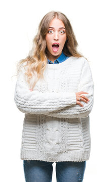 Beautiful young blonde woman wearing winter sweater over isolated background afraid and shocked with surprise expression, fear and excited face.