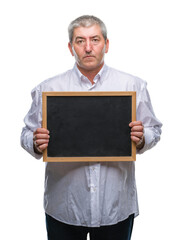 Handsome senior teacher man holding blackboard over isolated background with a confident expression on smart face thinking serious