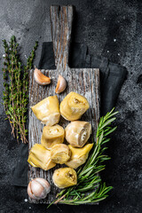 Artichokes hearts marinated with olive oil and herbs, pickled artichoke with garlic on wooden...