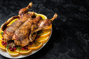 Christmas baked duck with herbs and fruits. Black background. Top view. Copy space