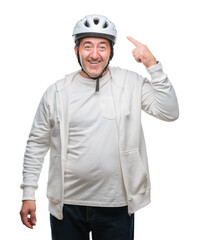 Handsome senior cyclist man wearing bike helmet over isolated background very happy pointing with hand and finger