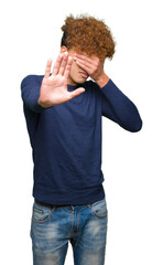 Young handsome man with afro hair covering eyes with hands and doing stop gesture with sad and fear expression. Embarrassed and negative concept.