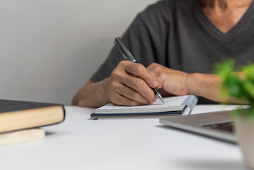 Woman hands with pen writing on notebook in the office.learning, education and work.writes goals, plans, make to do and wish list on desk..