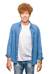 Young handsome man with afro hair wearing denim jacket winking looking at the camera with sexy...