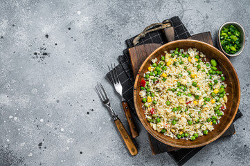 Chinese Fried rice with egg and vegetables in a wooden plate. Gray background. Top view. Copy space