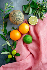 melon, oranges, lime on a background of pink linen fabric