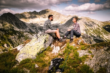 couple sitting on mountain top in amazing summer landscape